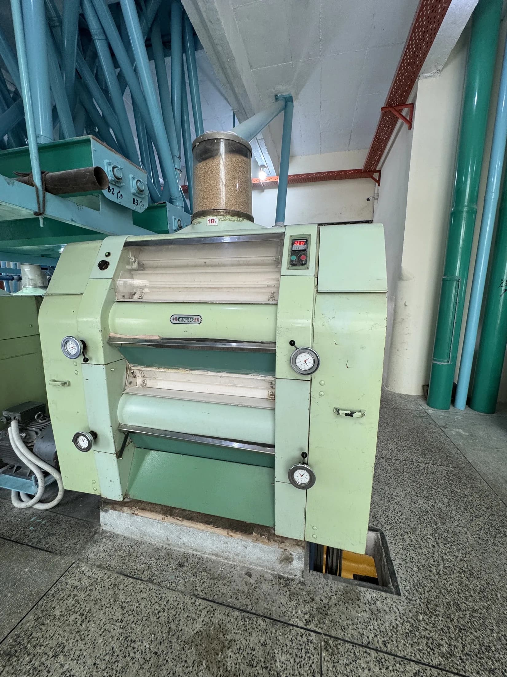 Bühler roller mill with grain feed hopper and analogue gauges on the milling floor.